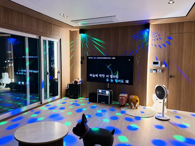 TV와 노래방 장비, 파란색과 초록색 조명이 보이는 실내 공간